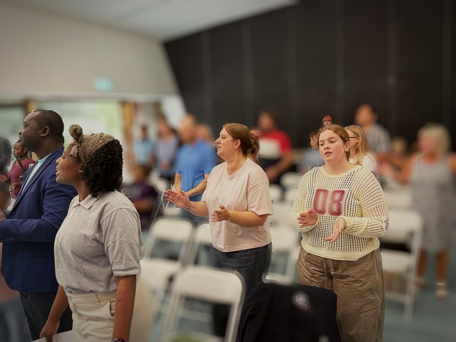 A woman and a girl clapping and singing during Sunday worship
